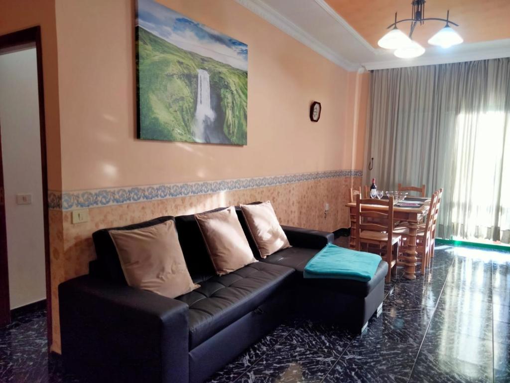 a living room with a black couch and a table at APARTAMENTOS La PEÑA D in La Guancha