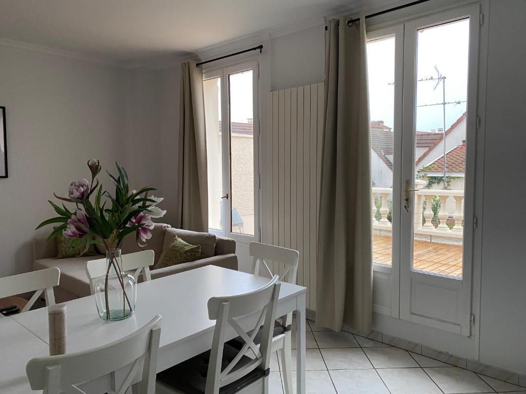 une salle à manger blanche avec une table et une fenêtre dans l'établissement Duplex cosy très proche de La Défense, à Nanterre