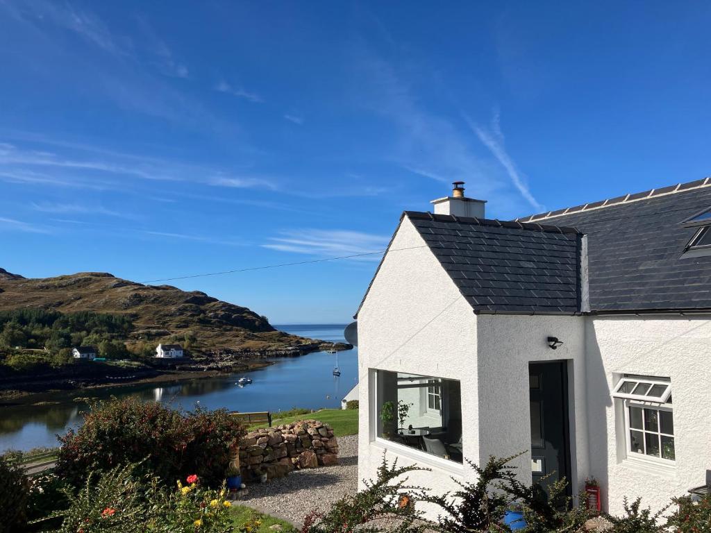 ein weißes Haus mit Blick auf einen Wasserkörper in der Unterkunft Waterfront cottage Applecross Peninsula in Ardheslaig
