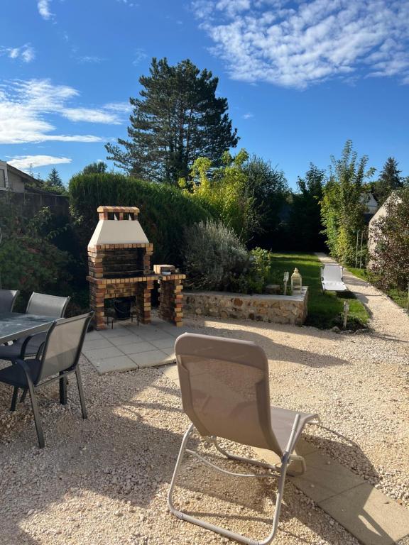 une chaise, une table et une cheminée dans la cour dans l'établissement Le Plaisancier Bourguignon, à Saint-Fargeau