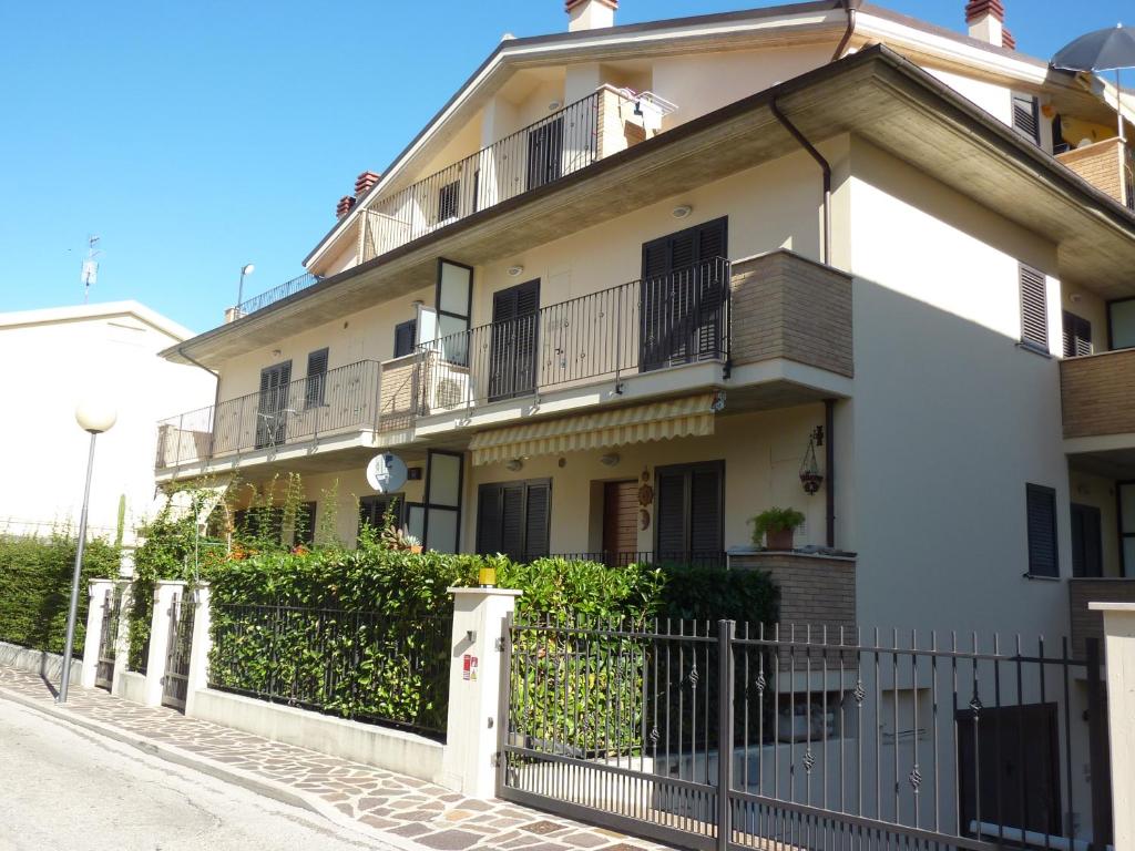 a white building with balconies and a fence at Ficus Pineto Vacanza in Pineto