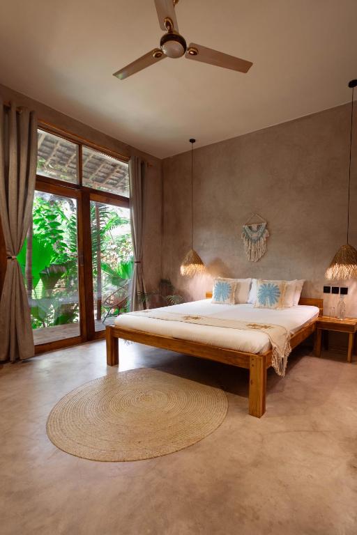 a bedroom with a large bed with a ceiling fan at The Garten Living in Paje