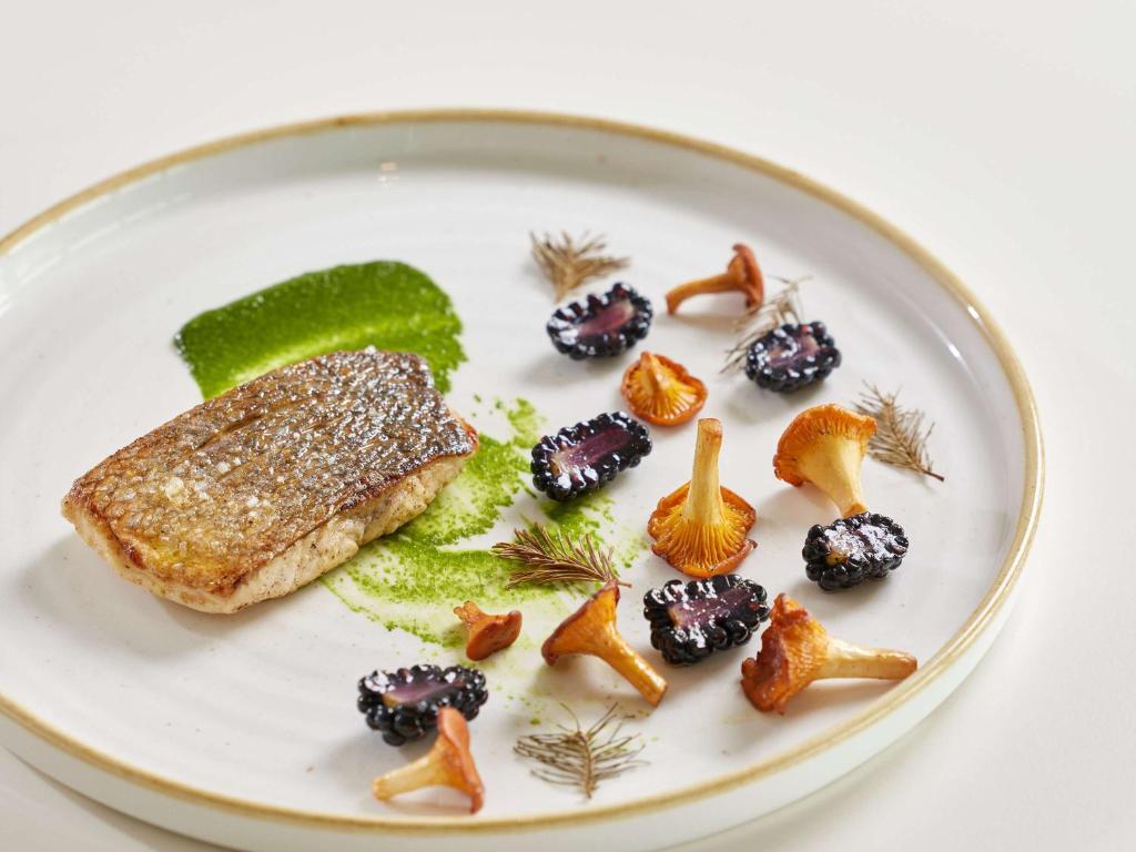 a plate of food with a piece of fish and fruit at Sofitel Golfe d'Ajaccio Thalassa Sea & Spa in Ajaccio