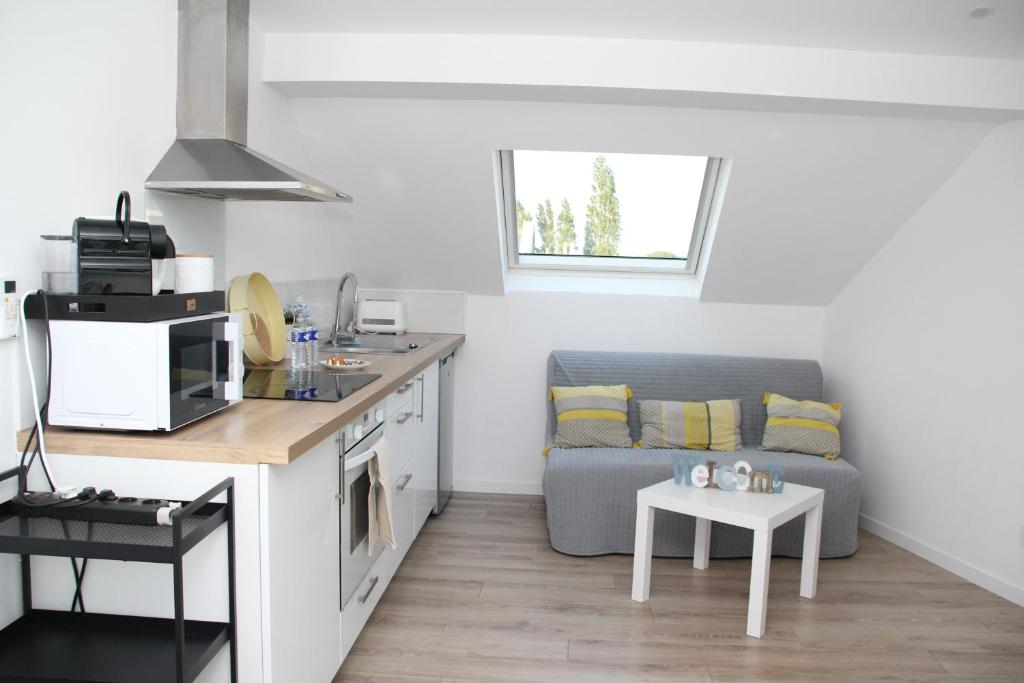 een keuken en woonkamer met een bank en een tafel bij L'appart T2 de la gare - Cambrai in Cambrai