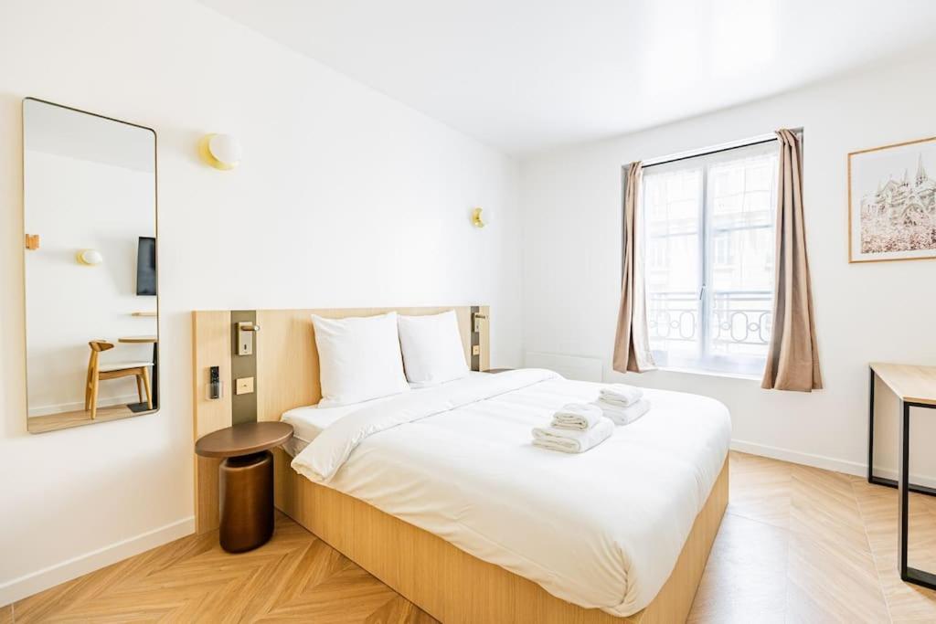 une chambre avec un grand lit blanc et un miroir dans l'établissement 154 Suite luxueuse-Etienne Marcel-Châtelet-Paris 3, à Paris