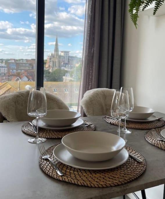 a table with plates and wine glasses on top of it at THE PAD by the beach Penthouse apartment with sunset and city views in Bournemouth