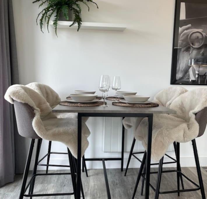 a dining room table with chairs and wine glasses at THE PAD by the beach Penthouse apartment with sunset and city views in Bournemouth