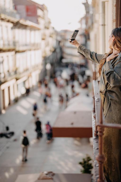 a woman taking a picture of a city street with her cell phone at Casa da Companhia, Vignette Collection by IHG in Porto