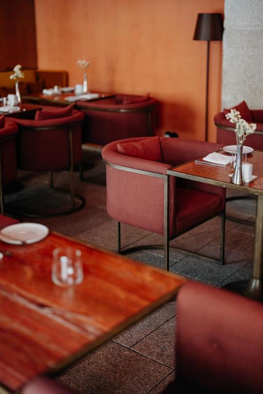 a restaurant with red couches and tables and tablesearcher at Casa da Companhia, Vignette Collection by IHG in Porto