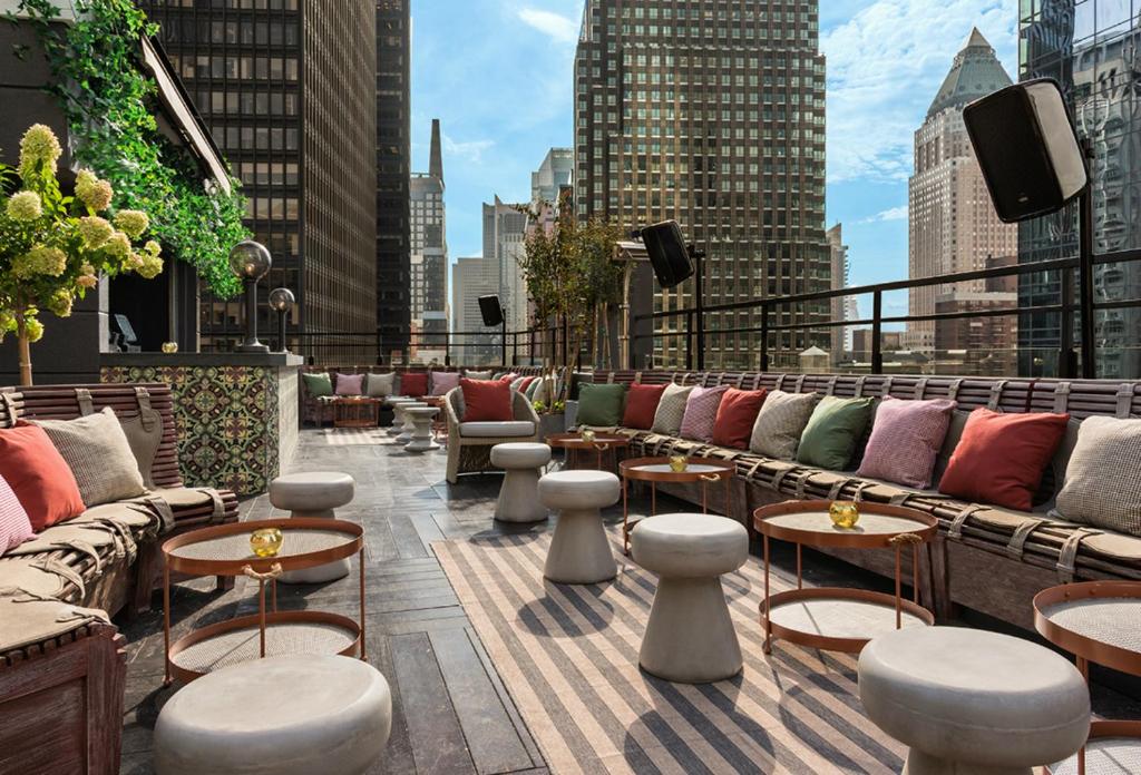 a rooftop patio with couches and tables on a building at Dream Midtown in New York