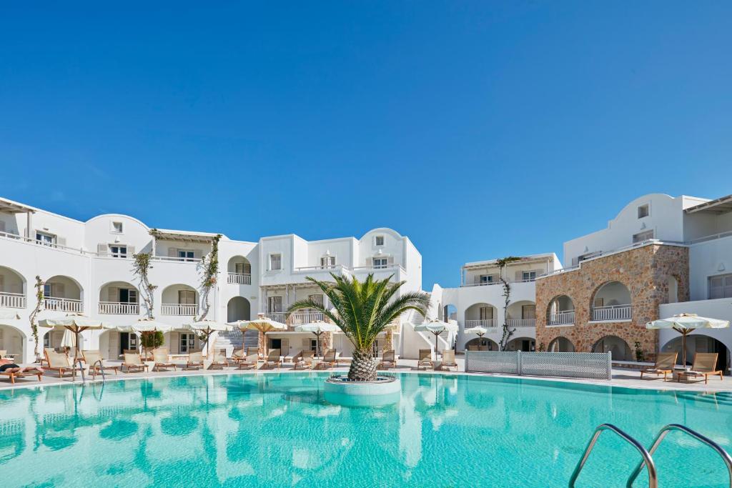 a large swimming pool in a hotel with white buildings at Aegean Plaza Hotel in Kamari