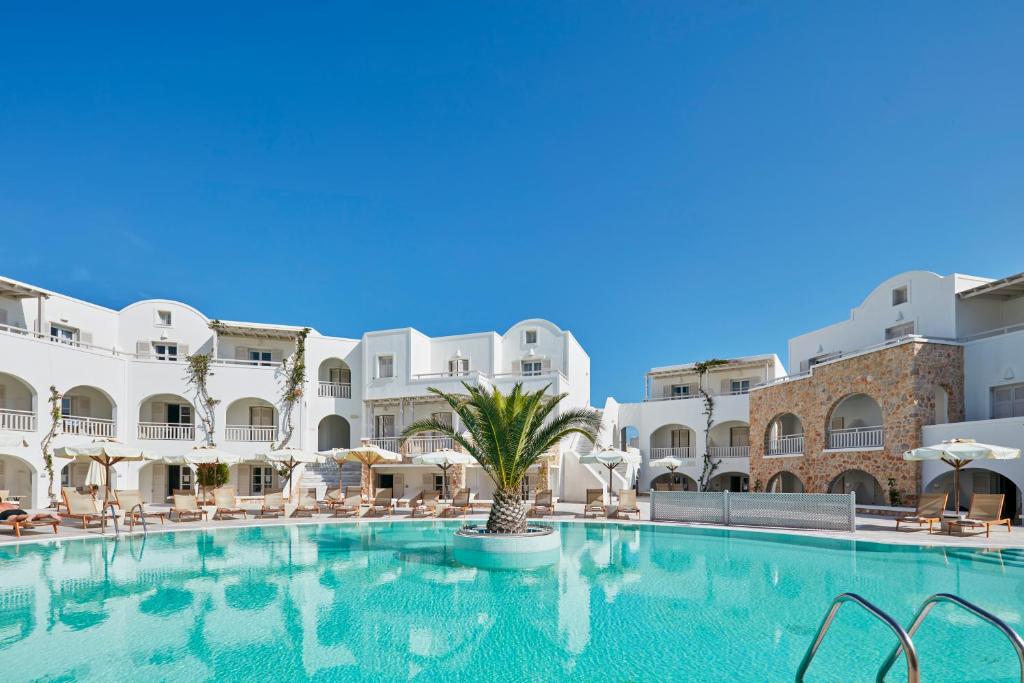 duży basen w hotelu z białymi budynkami w obiekcie Aegean Plaza Hotel w mieście Kamari