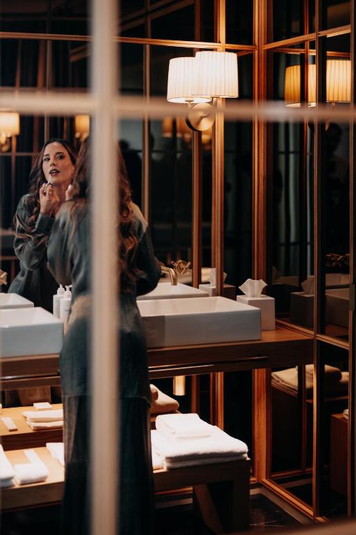 a woman looking at her reflection in a bathroom mirror at Casa da Companhia, Vignette Collection by IHG in Porto