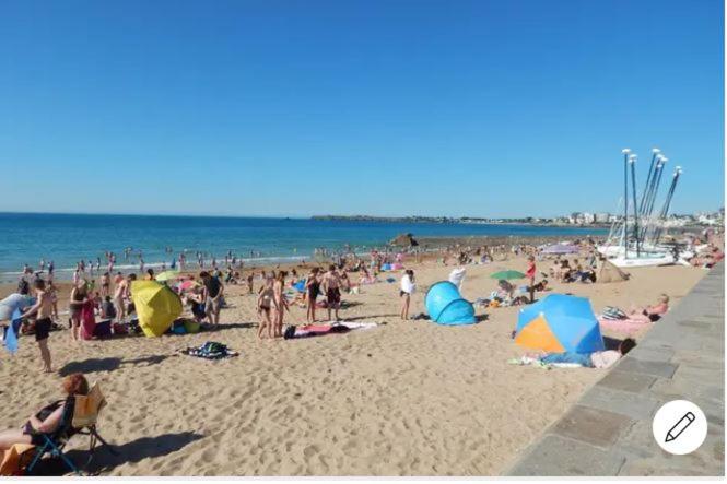 Une foule de gens sur une plage avec des parasols dans l'établissement ST Malo Bel appartement prés gare plage du sillon parking privé, à Saint-Malo