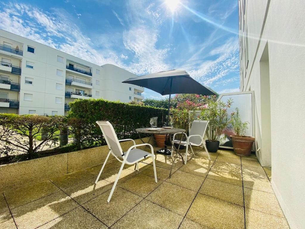 un patio avec une table, des chaises et un parasol dans l'établissement Casa Coeur Maine, à Angers