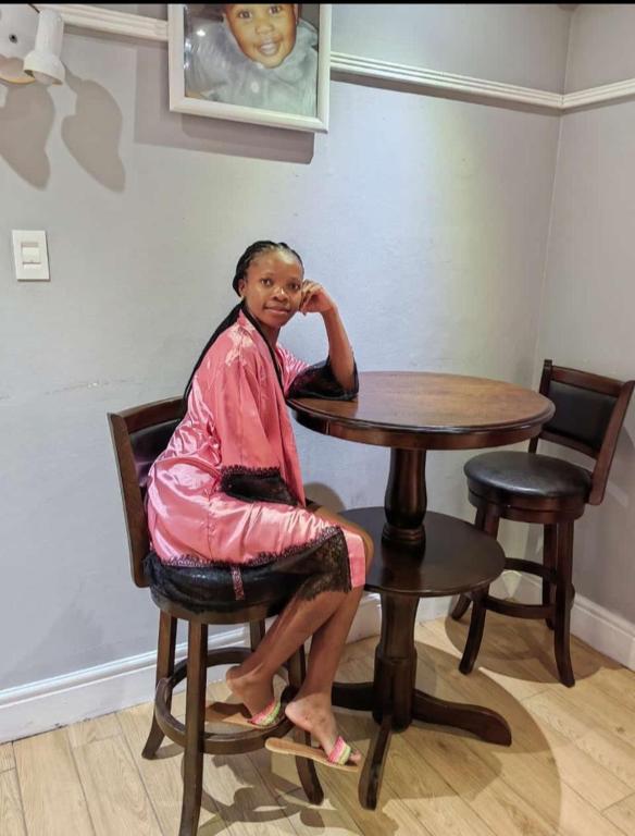 a woman sitting at a table in a chair at Tara's Terrace Guest House in King Williamʼs Town