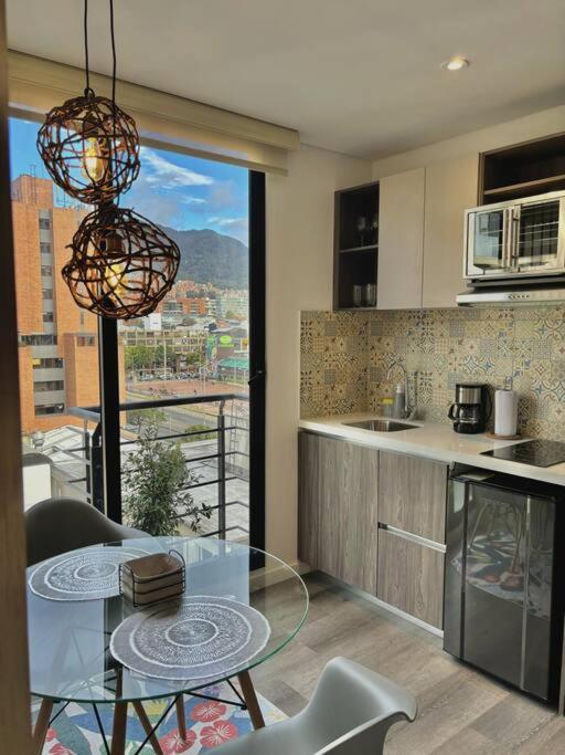 une cuisine avec une table en verre et une vue dans l'établissement Luxury loft en el Parque Virrey, à Bogotá