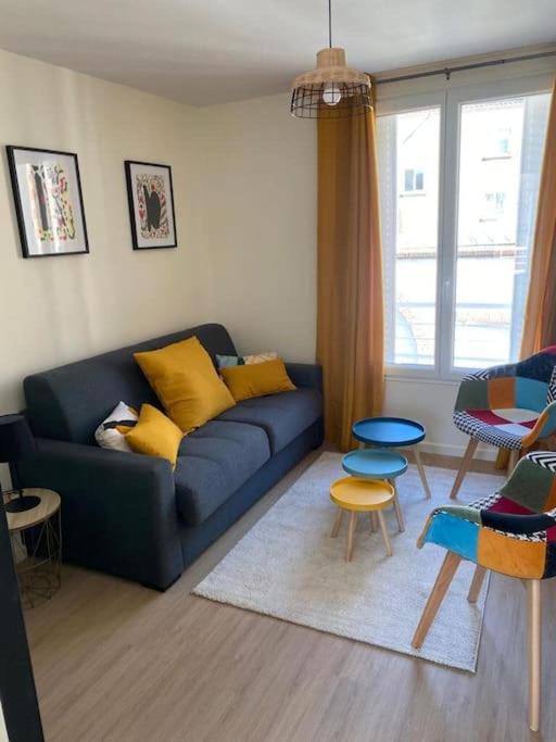 un salon avec un canapé bleu et des chaises dans l'établissement Charming Apartment Gacé II 4P, à Gacé