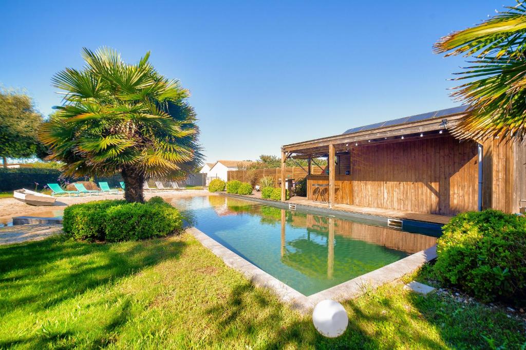 une piscine dans une cour avec un bâtiment dans l'établissement Maison pour 10 - Bassin naturel et détente, à Saint-Vincent-sur-Jard