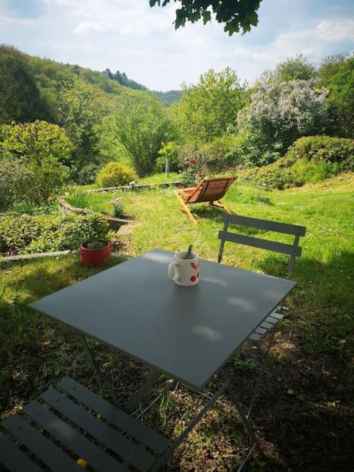 - une table de pique-nique avec une tasse à côté d'un banc dans l'établissement Confortable maison à la campagne, à Les Fougères