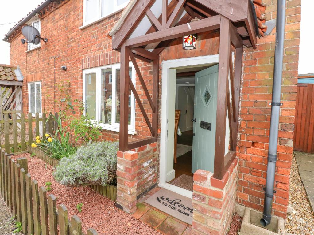 una casa di mattoni con un tendone sopra la porta di Easter Cottage a Dersingham