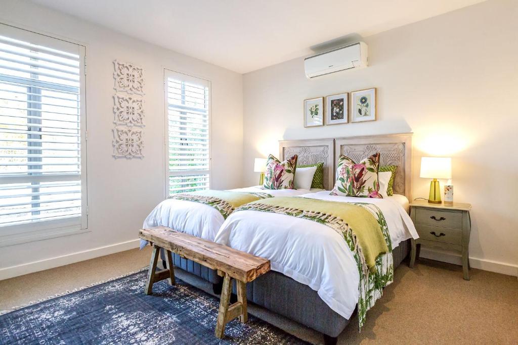 a bedroom with a large bed and a bench at Waddle Inn Luxury apartment in Franschhoek in Franschhoek