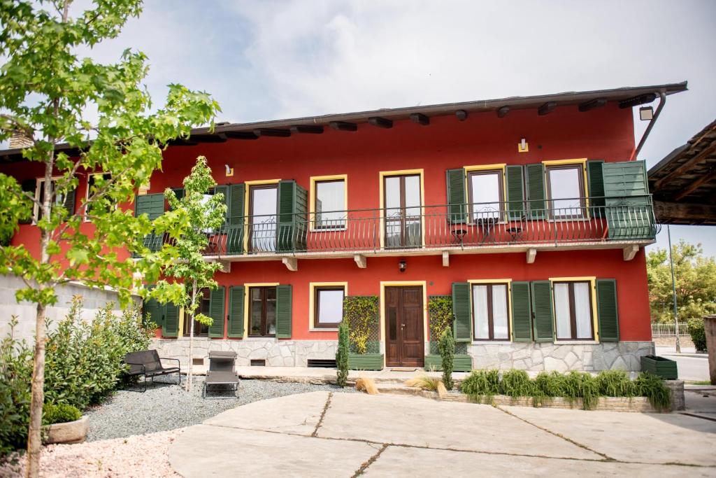 a red house with green windows and a balcony at Agriturismo Ca' del Clat in Bagnolo Piemonte