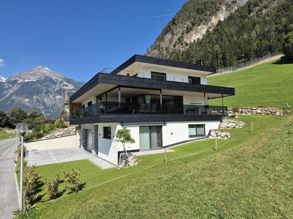 una casa en una colina con montañas al fondo en Zillernest Apartment, en Bruck am Ziller