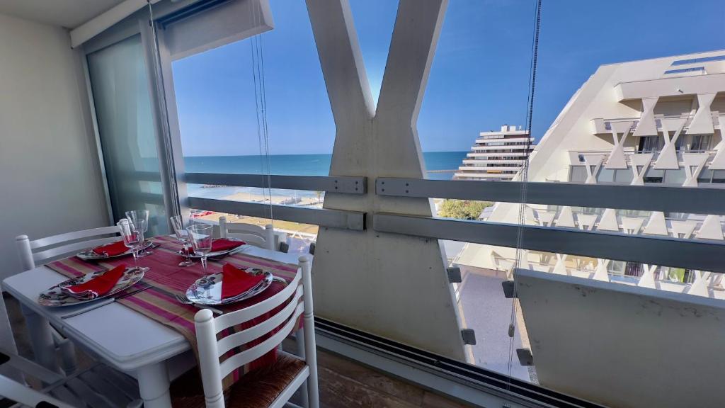une table et des chaises sur un balcon avec vue sur l'océan dans l'établissement Le Clair Horizon-YourHostHelper, à La Grande Motte