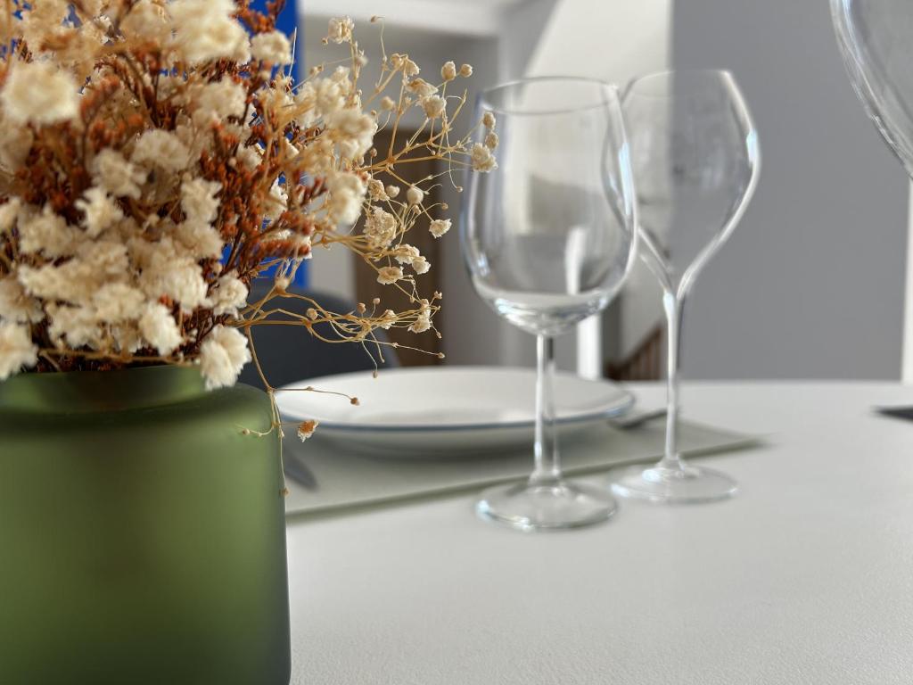 une table avec deux verres à vin et un vase avec des fleurs dans l'établissement Voie des Sacres - Cathédrale de Reims, à Reims