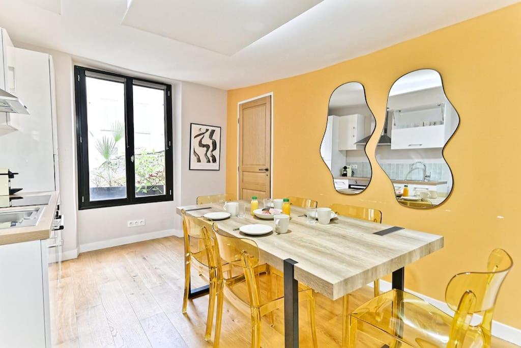 - une salle à manger avec une table et deux miroirs dans l'établissement Appartement 3 chambres Paris 2ème - III, à Paris