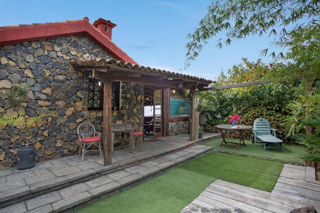 a patio with a table and chairs and a stone wall at Finca el pilar in La Guancha