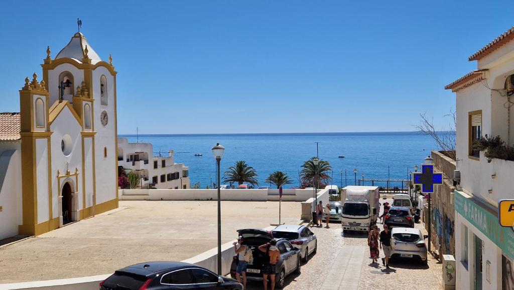 a church and cars parked on a street next to the ocean at Apartamento Cristino in Luz