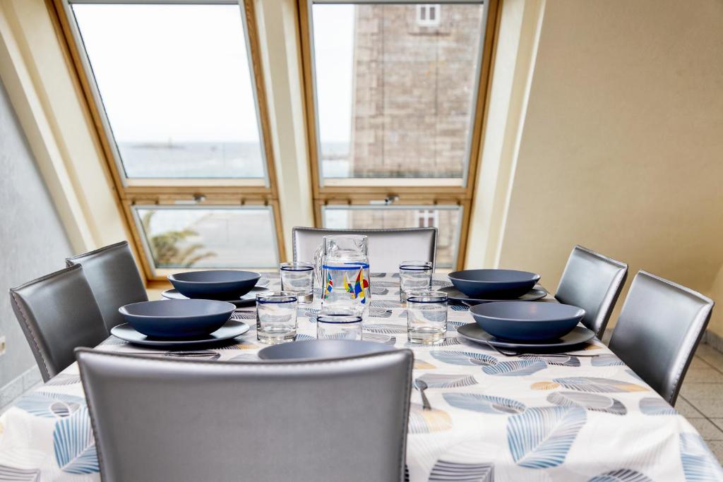 - une table avec des chaises, des bols et des verres dans l'établissement Rêves de marins T3 avec parking privé en hyper centre, à Roscoff