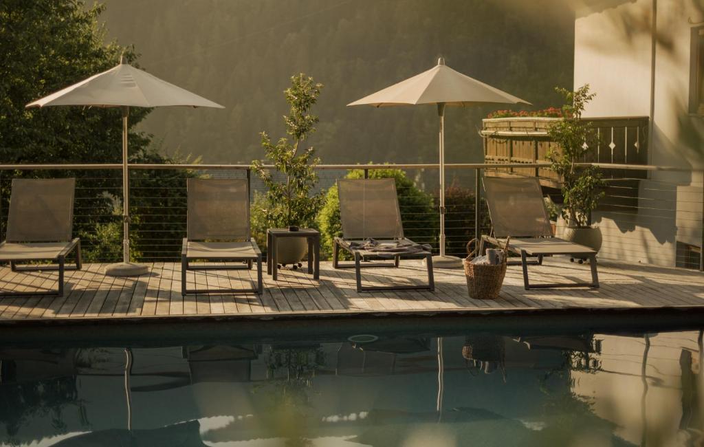 a group of chairs and umbrellas next to a pool at Moarhof with Brixen Card in Feldthurns