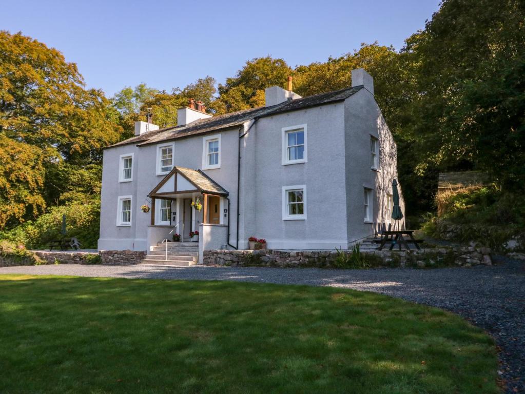 une maison blanche avec une pelouse devant dans l'établissement Dalegarth Hall Farm Cottage 1, à Holmrook