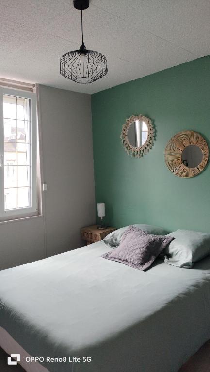 une chambre avec un lit et deux miroirs au mur dans l'établissement Maison de village cosy, à Saint-Eustache-la-Forêt
