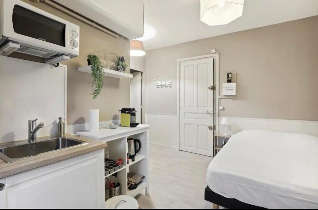 - une cuisine avec évier et un lit dans une chambre dans l'établissement Jeu de Paume, à Versailles