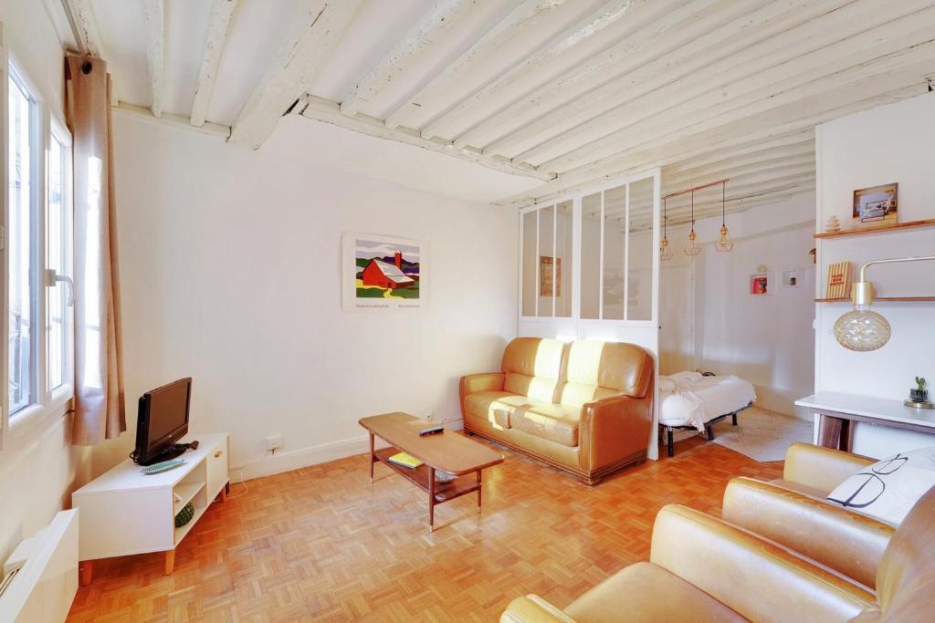 un salon avec un canapé et une télévision dans l'établissement GuestReady - Appartement arty cosy et très central, à Paris