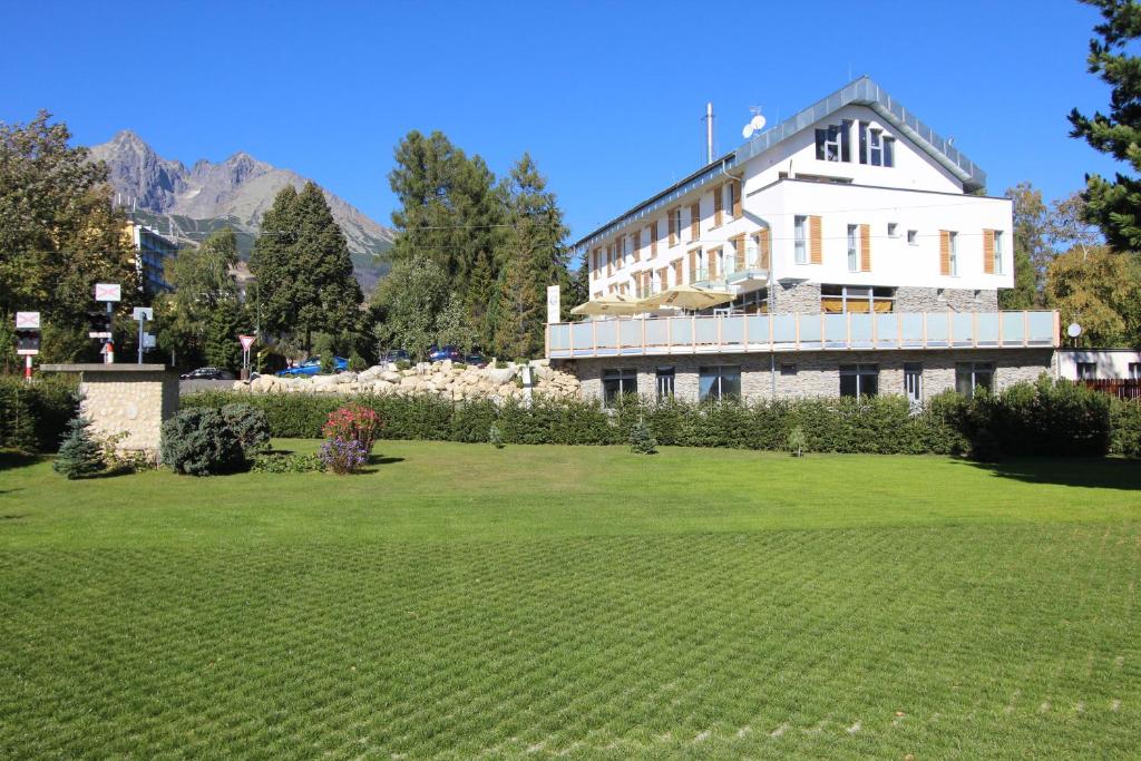 a large building with a lawn in front of it at Aparthotel Belveder in Vysoke Tatry - Tatranska Lomnica.