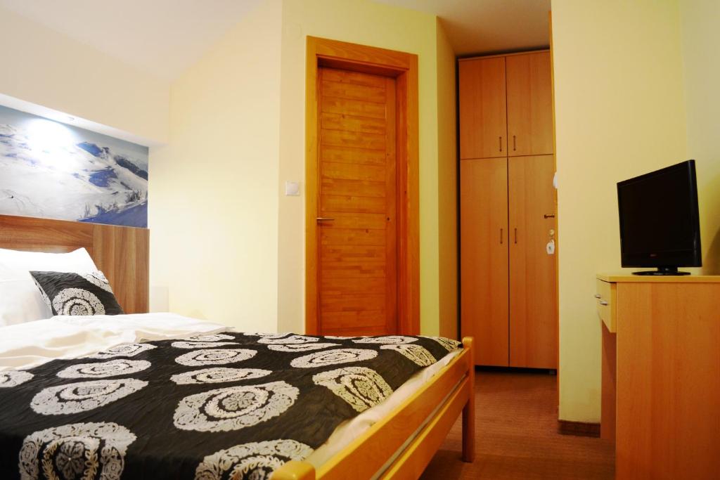 a bedroom with a bed and a flat screen tv at Guesthouse Lucic in Jahorina