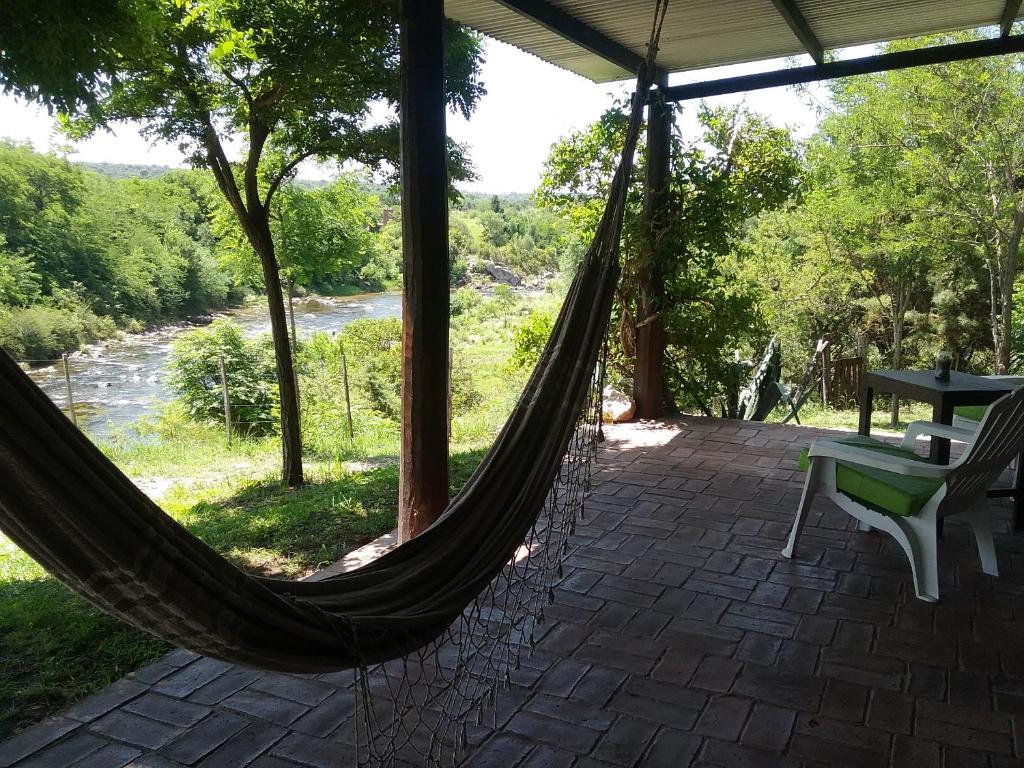 a hammock on a patio with a view of a river at Cabañas Nueve Lunas in Santa Rosa de Calamuchita