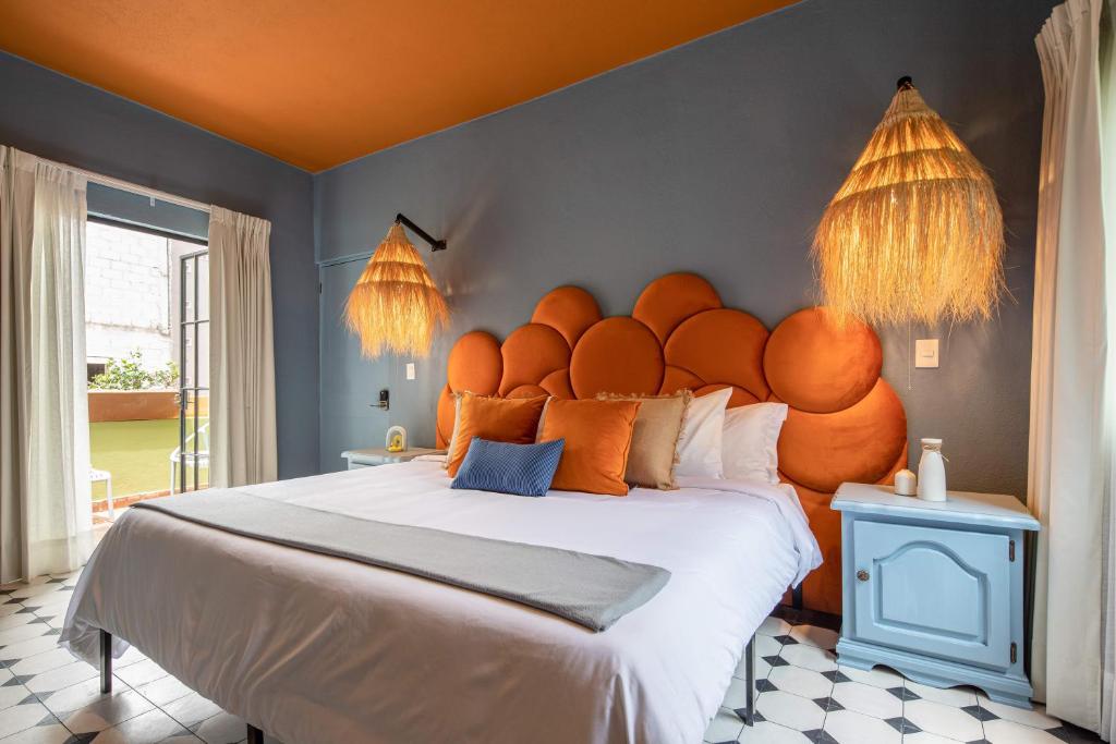 a bedroom with a large bed with an orange headboard at HOLT Art Deco Retreat in Vibrant 3 Bedroom Villa in San Miguel de Allende
