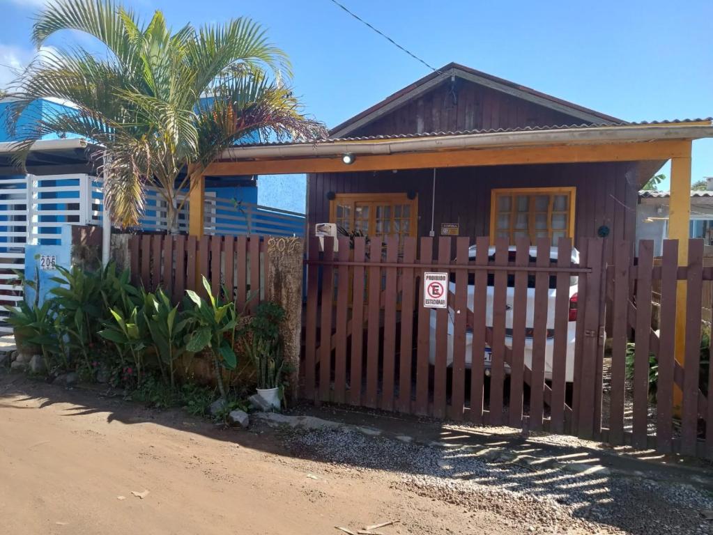 a house with a wooden fence and a palm tree at Casa próximo á praia MOÇAMBIQUE SC in Florianópolis