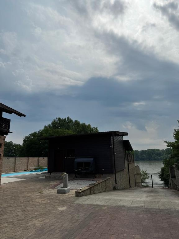 een klein zwart gebouw naast een waterpartij bij Julies Villas in Štúrovo