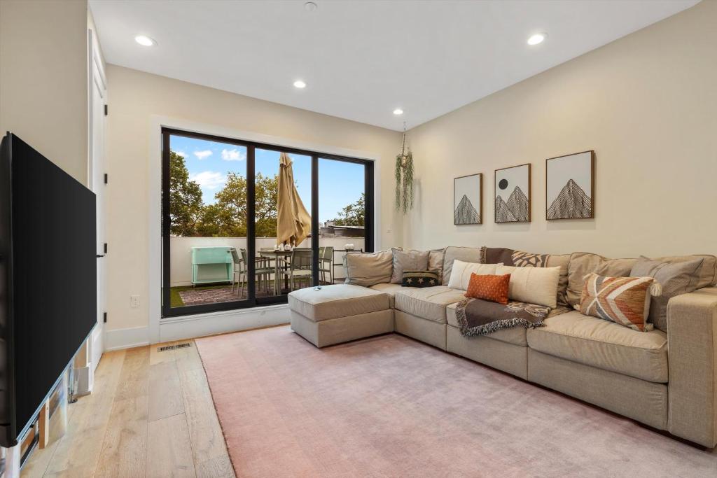 a living room with a large couch and a large window at Central DC 5-BR Townhome - Walk to METRO-rail in Washington, D.C.