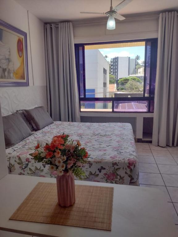 a bedroom with a bed and a vase with flowers on a table at Flat na Praia do Farol da Barra in Salvador