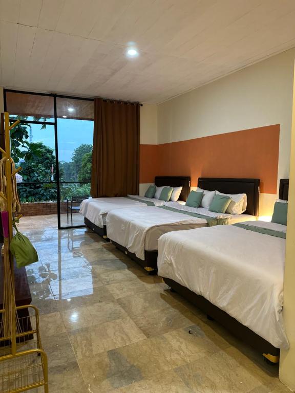 a hotel room with three beds and a balcony at Little Bali Villa - Luxury Lake View at Bogor in Kalisuren 2