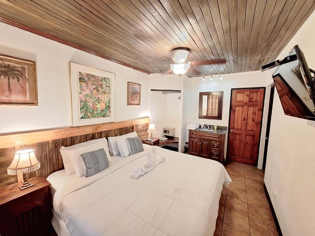 a bedroom with a white bed with a wooden ceiling at Colours Oasis Resort ADULT ONLY in San José