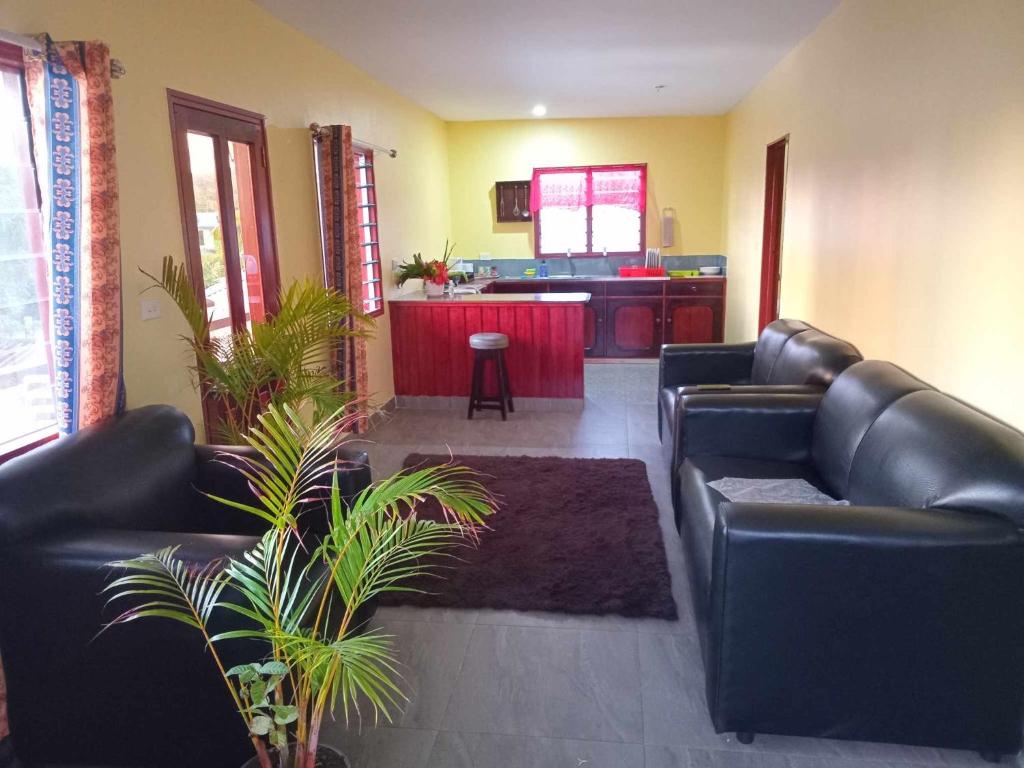 a living room with black leather couches and a kitchen at Dream Paradise Apartment in Korotogo